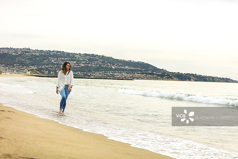 女性千禧一代在充满生命的海滩上行走在海岸线上的图像系列图片素材