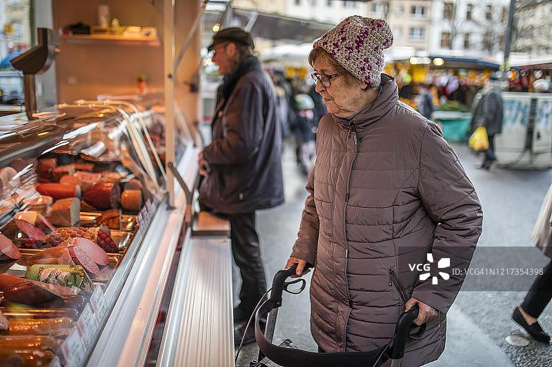 德国北莱茵-威斯特法伦州科隆的每周集市上，老汉看着屠夫的香肠图片素材