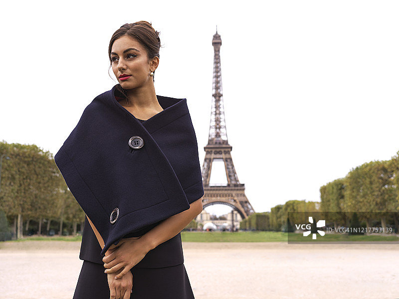 法国巴黎，白天，时髦的女人站在埃菲尔铁塔前图片素材