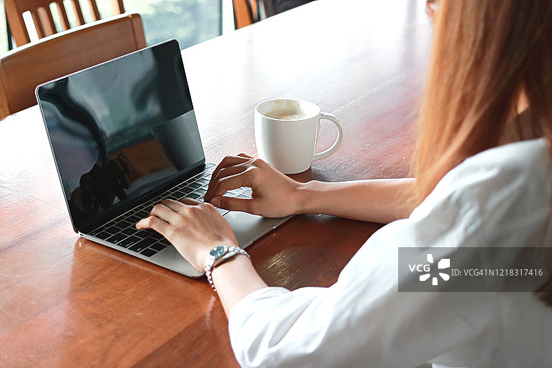 裁剪的图像年轻的商业女性工作与笔记本电脑在办公室的工作场所。图片素材