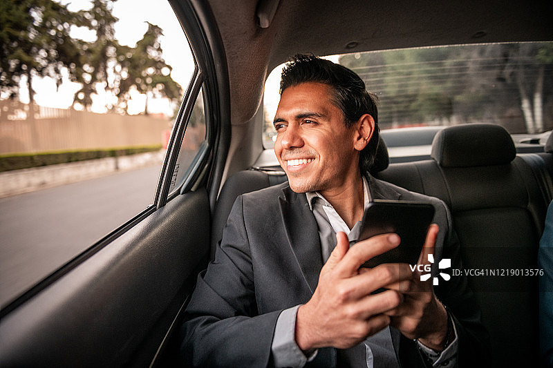 微笑的墨西哥男人发短信。图片素材