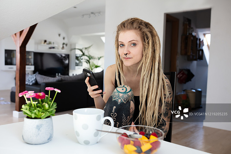 一个有纹身的女人在家里用手机的肖像图片素材