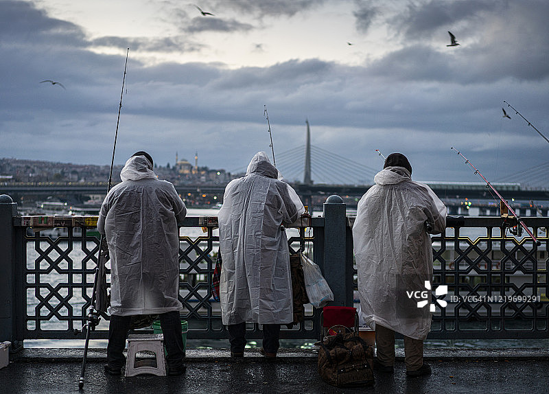 土耳其伊斯坦布尔，一群男子晚上在加拉塔桥上钓鱼图片素材