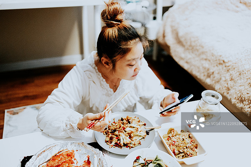 年轻的亚洲女子在卧室享受中国食物图片素材