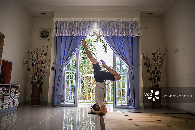 一个亚洲华人在客厅里练瑜伽。因新冠肺炎大流行在家培训。图片素材