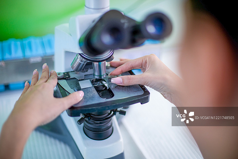 女科学家在实验室里研究和观察显微镜。图片素材
