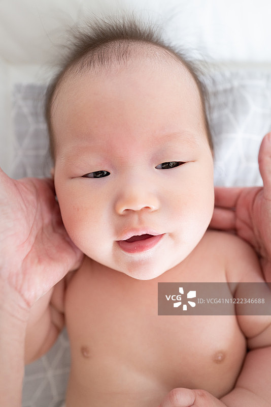 一个亚洲婴儿在身上涂霜图片素材