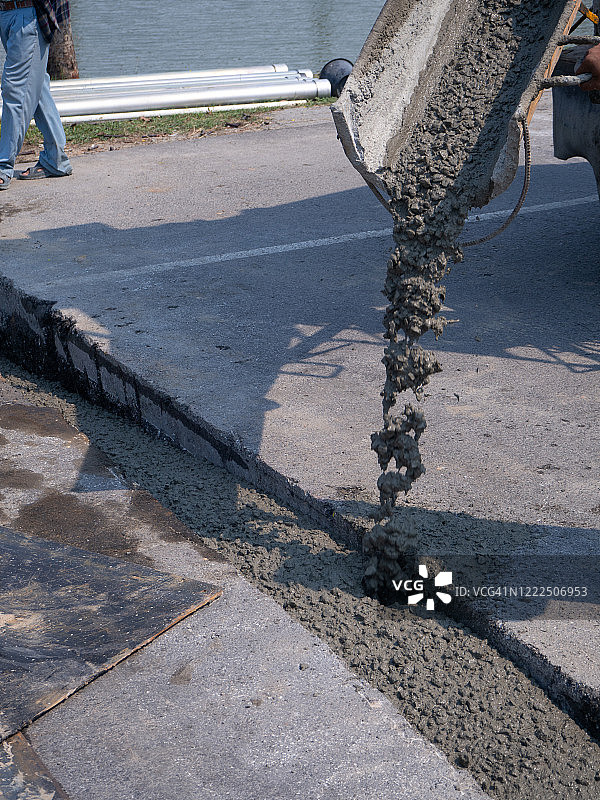建筑工人在住宅区街道升级过程中浇注水泥。图片素材