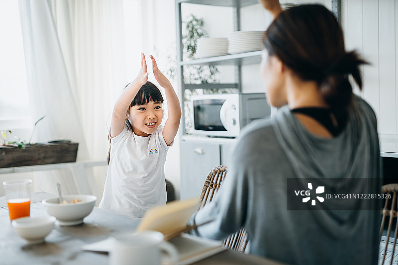 年轻的亚洲母亲和小女儿在厨房里吃早餐时玩得很开心图片素材