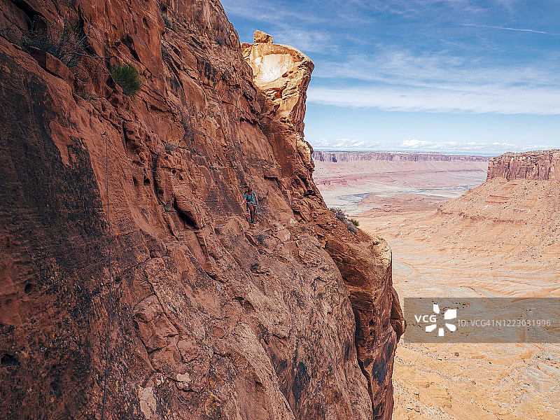 一名妇女在南犹他州沙漠塔上爬过一个狭窄而暴露的窗台图片素材