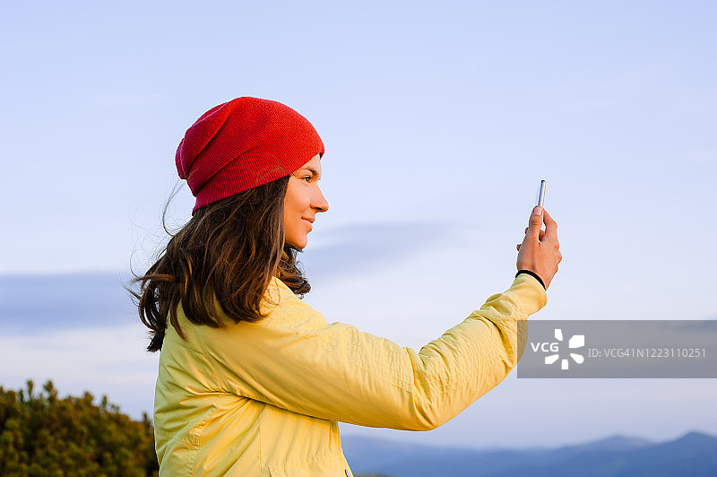 十几岁的女孩在山顶上使用智能手机图片素材