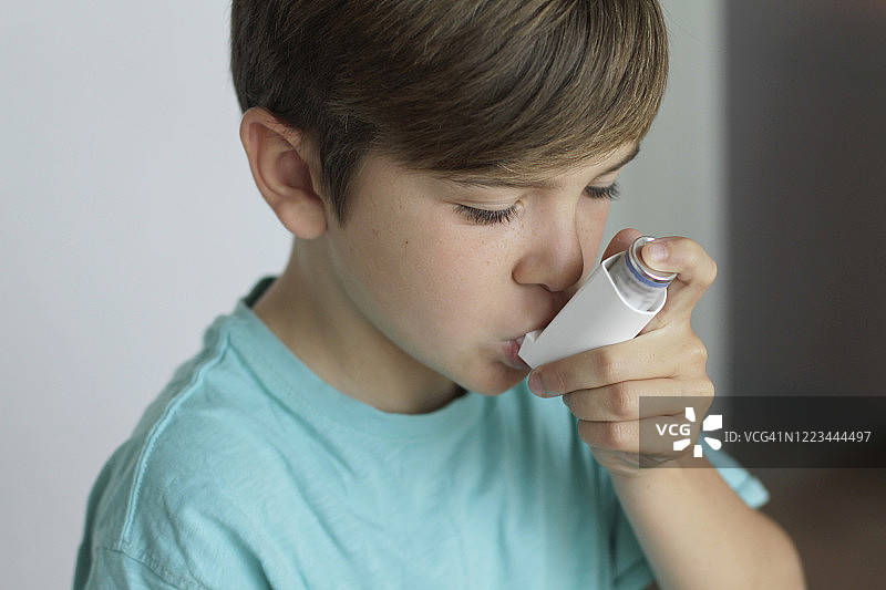 男孩用吸入器治疗哮喘图片素材