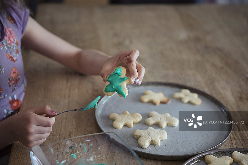 孩子用绿色糖衣装饰刚烤好的人形自制饼干图片素材
