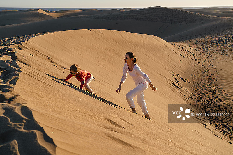 母亲和女儿爬沙丘，大加那利岛，西班牙图片素材