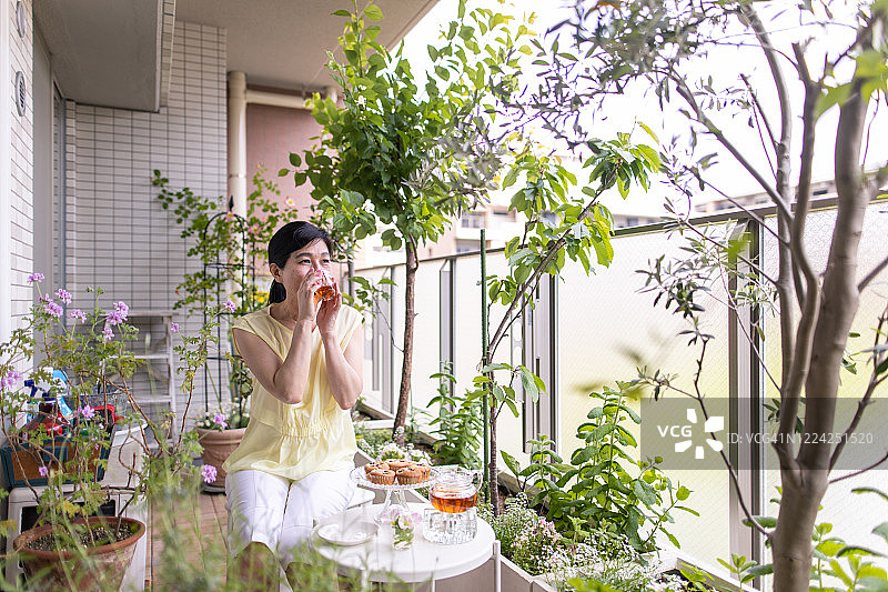 在阳台上喝茶的成熟女人图片素材