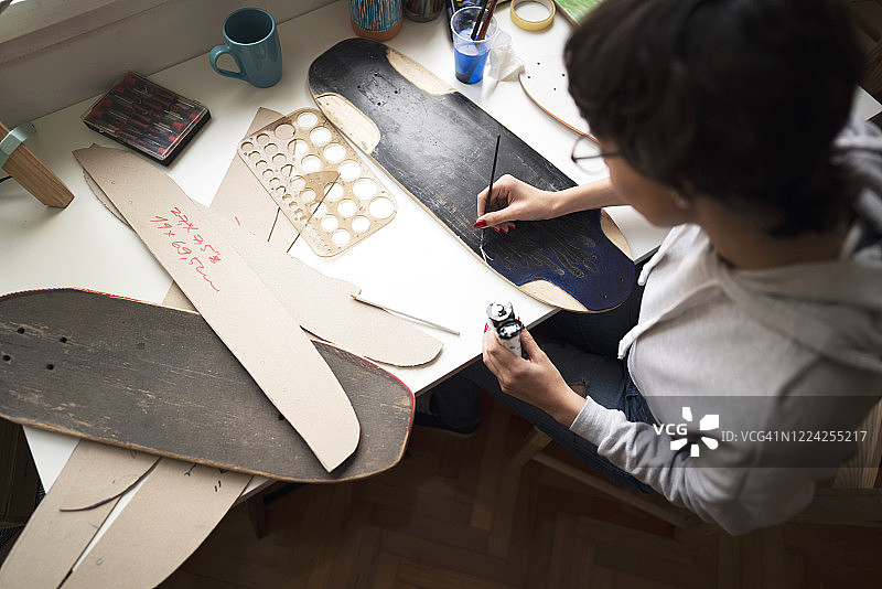 年轻女子在她的工作室滑板板上作画图片素材