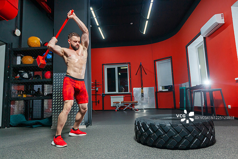 强壮肌肉的男子在现代健身房进行大锤锻炼的全长肖像图片素材