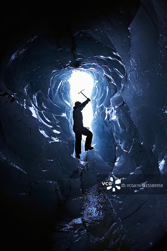 在一个小冰洞的入口处，一个成年男子的剪影图片素材