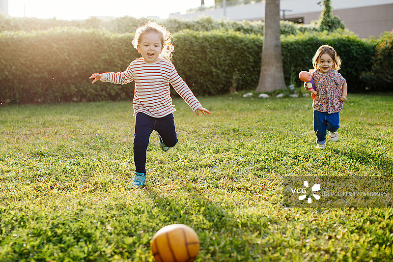 小女孩们在夏天的公园里玩球。孩子和兄弟姐妹在户外玩耍。图片素材