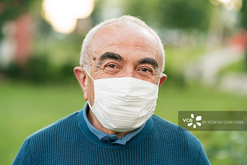友善的老人戴着口罩，以防止病毒和细菌图片素材