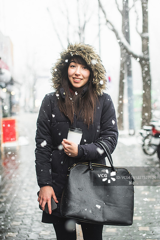 一个微笑的女人的肖像，穿着毛皮大衣站在雪地里，梨泰院，韩国图片素材