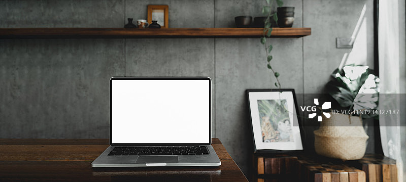 笔记本电脑空白白屏幕上的桌子在咖啡馆的背景。笔记本电脑与空白屏幕上的咖啡店模糊背景。图片素材