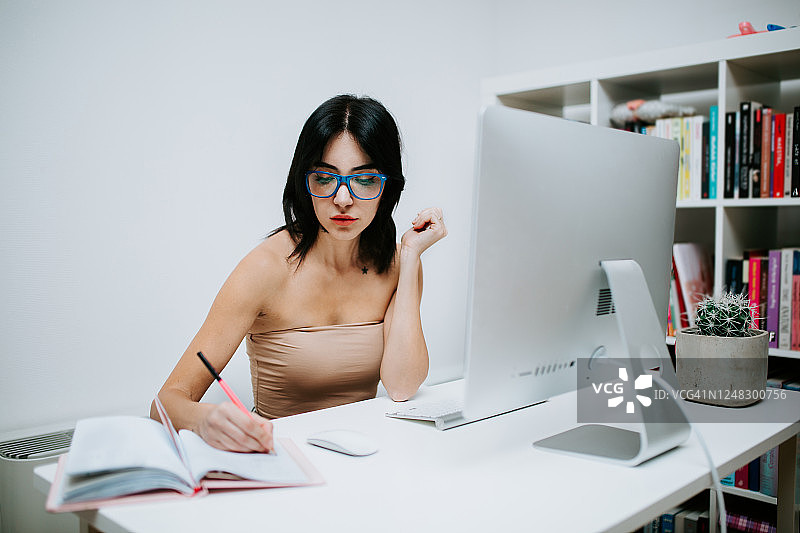 戴蓝眼镜在家用电脑工作的女人图片素材