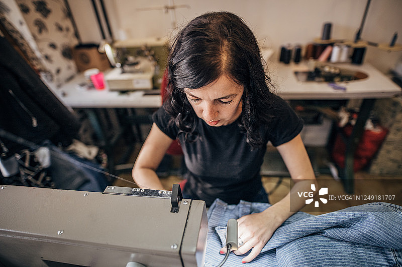 在裁缝车间缝纫机上工作的妇女图片素材