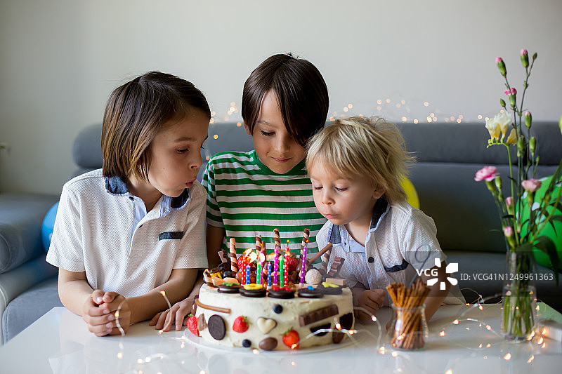 可爱的孩子，用自制的生日蛋糕来庆祝他的生日，上面有很多巧克力，饼干和草莓图片素材