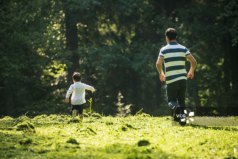 快乐的父亲和他的儿子在户外玩接球图片素材