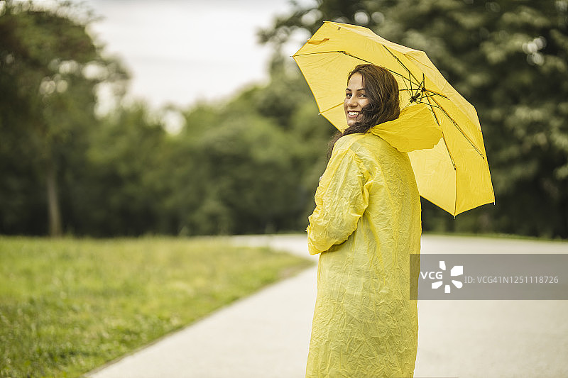 拿着黄伞，穿着黄雨衣，享受着雨的女人图片素材