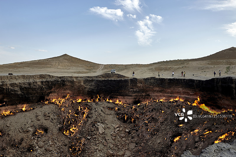 土库曼斯坦，日落时分，游客们正在参观燃烧着的达尔瓦扎火山口图片素材