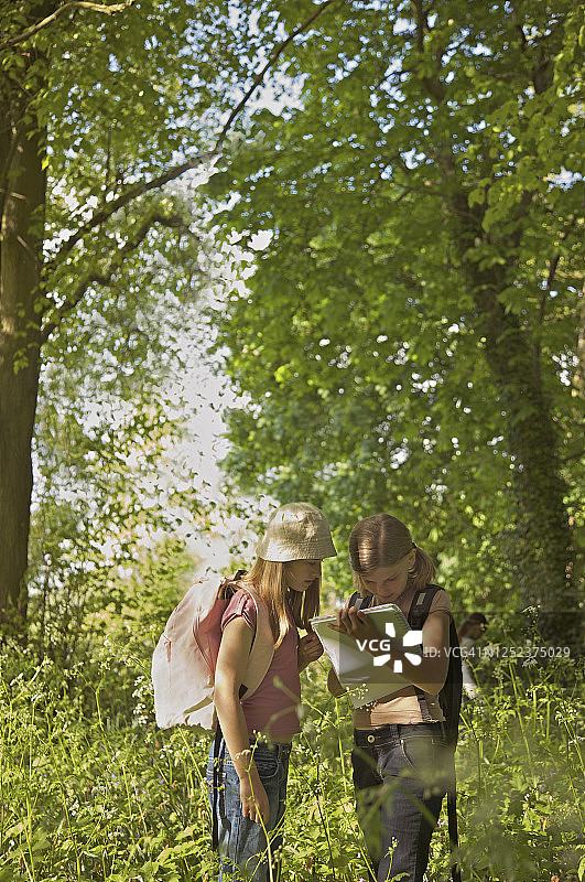带着笔记本在树林里实地旅行的女孩们图片素材
