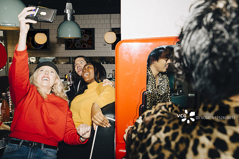 微笑的女性与朋友在咖啡馆自拍图片素材