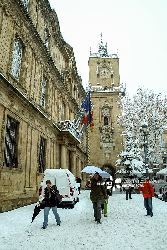 人们在一场不寻常的雪下行走在市政厅广场的钟塔前。图片素材