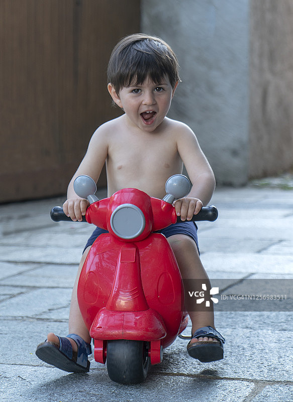 小男孩在摩托车上玩玩具图片素材