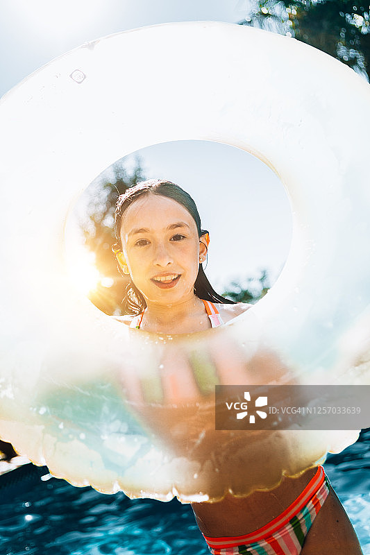 快乐的女孩在度假期间在泳池边玩充气环图片素材