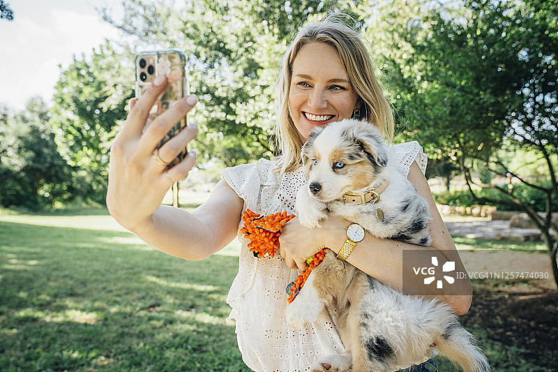 一名女子拿着澳大利亚牧羊犬狗用智能手机自拍图片素材