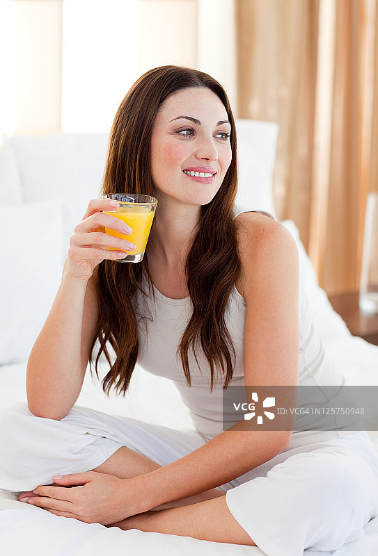 漂亮女人在床上喝橙汁图片素材
