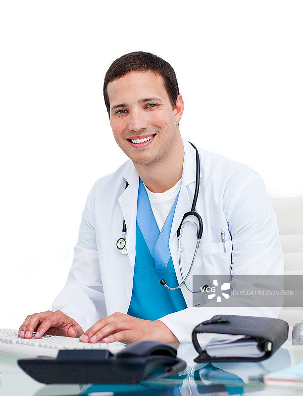微笑的医生在他的办公室电脑上工作图片素材