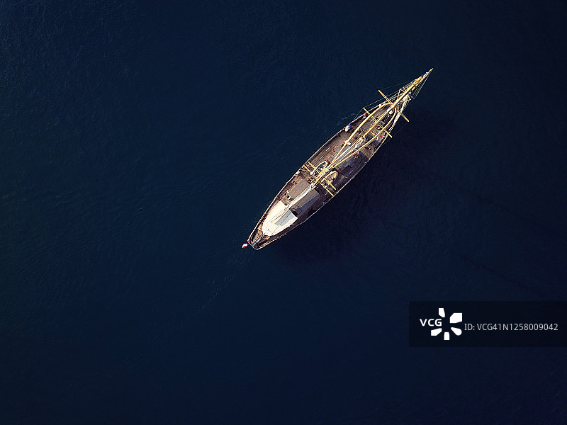 航拍俯瞰一艘帆船在移动中被深蓝色的水包围。图片素材