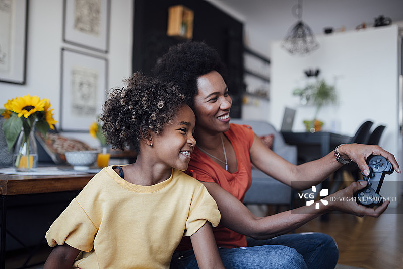一个快乐的非裔美国母亲和女儿在家里一起玩电子游戏图片素材