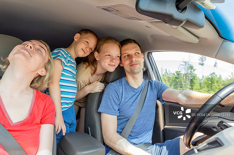 微笑的年轻家庭和两个心爱的孩子一起在一个夏日阳光明媚的日子里乘车旅行图片素材