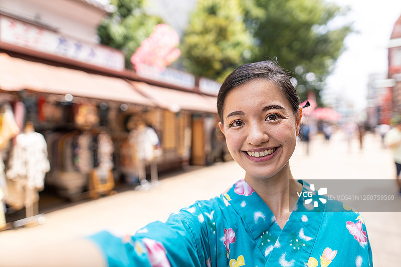 在传统的日本街道上，年轻女子在浴方谈论自拍照的肖像图片素材