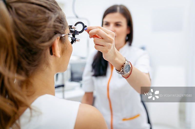 女眼科医师用光视仪检查病人视力图片素材