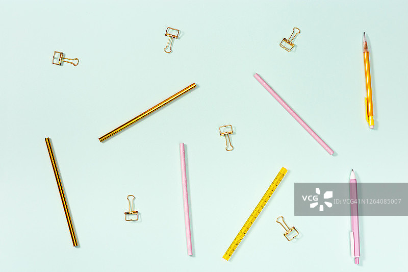 平铺学校或办公室用文具。粉色和金色的铅笔，钢笔和金属回形针。图片素材