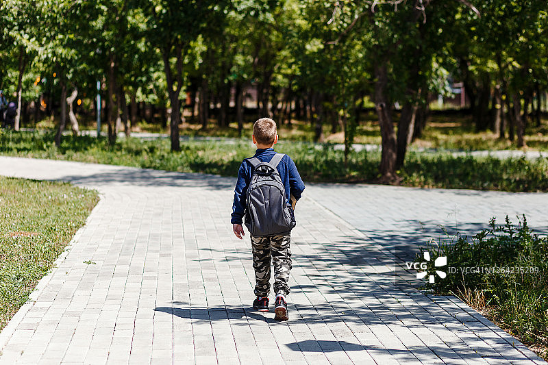 一个背着大背包的男生走在公园的小路上。图片素材
