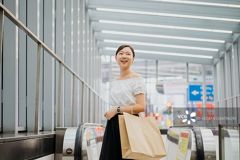 年轻的亚洲女子拿着一个纸袋走出地铁站图片素材
