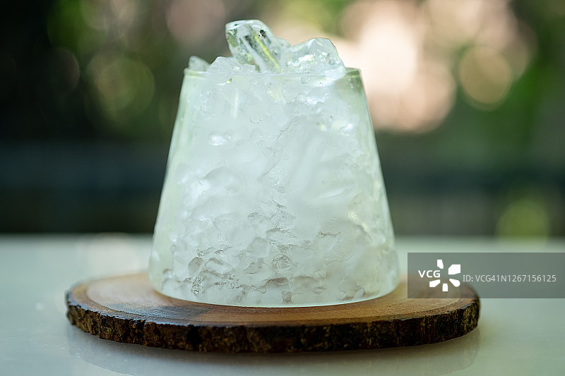 桌上放着一杯冰，在大自然的绿色背景中图片素材