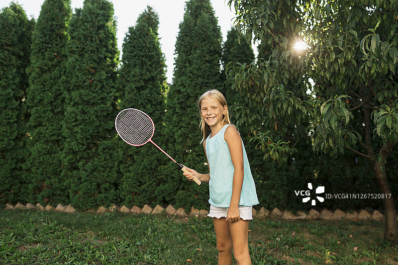 一个快乐的白人女孩在后院打羽毛球图片素材